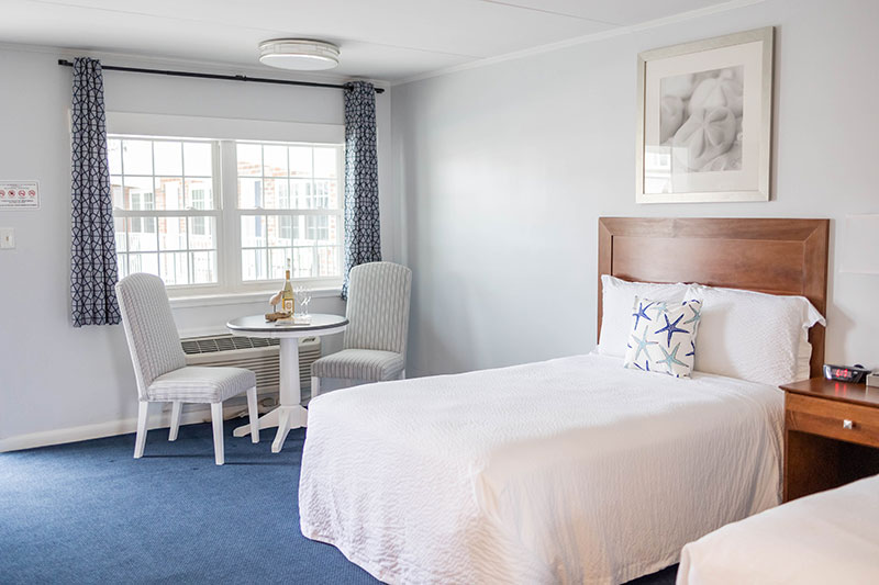 Hotel room with two double beds and a small table with two chairs beneath the window